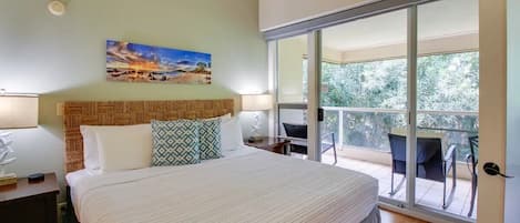 A bedroom with a large bed, a painting on the wall, and a balcony with chairs.