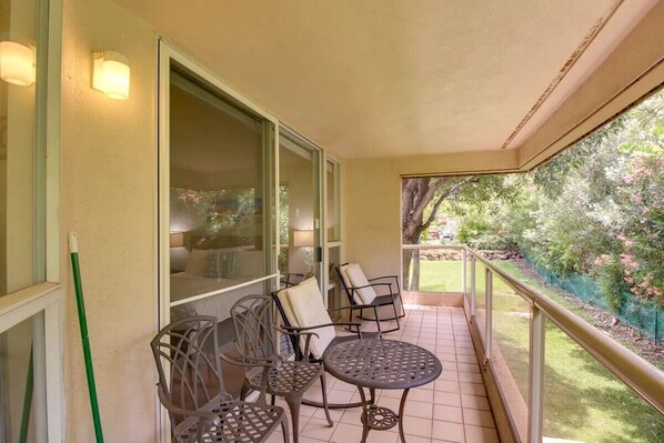 A balcony with a glass door, two tables, and two chairs.