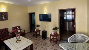 Een woonkamer met een aan de muur bevestigde televisie, een salontafel, twee fauteuils en een vloer met een patroon.