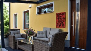 Una zona relax all'aperto accogliente, con mobili in vimini, un tavolo in vetro e un vaso di fiori.