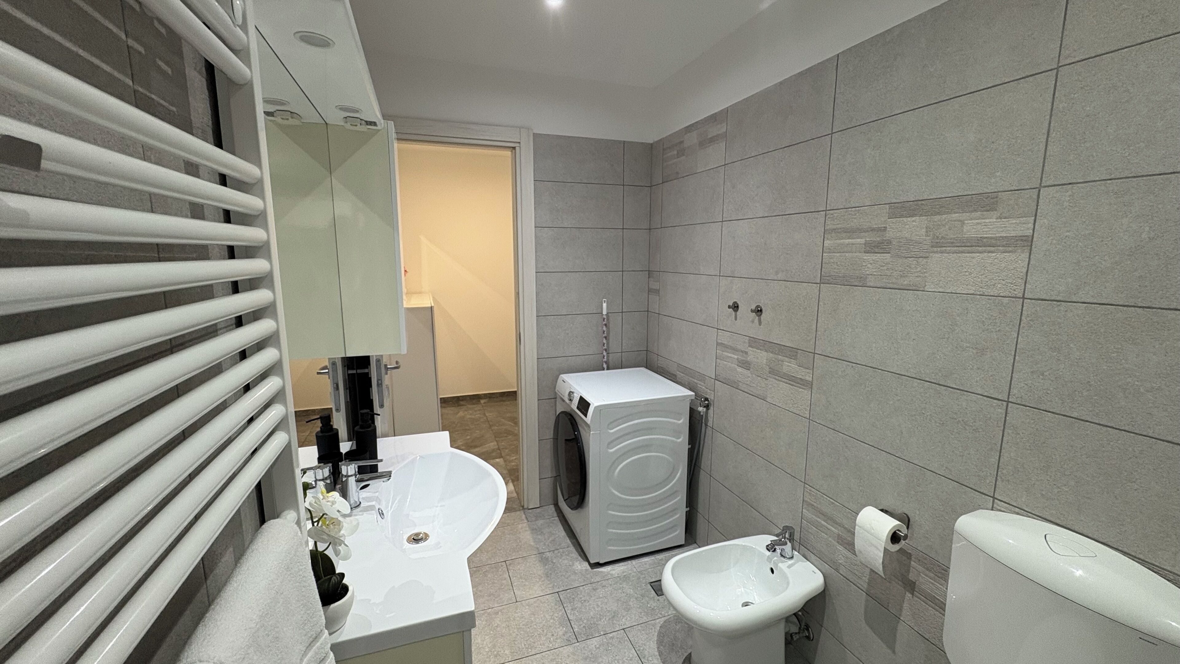 A modern bathroom with a built-in washing machine, a sink, and a toilet.