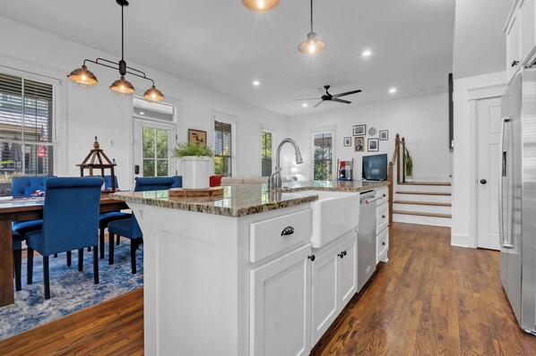 A spacious kitchen with a central island, white cabinetry, and a dining area with blue chairs.
