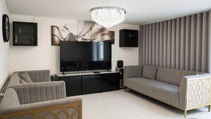 Een moderne woonkamer met een flatscreen televisie, twee banken, een salontafel en een decoratief wandkunstwerk.