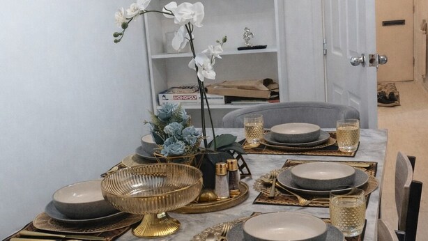 Een eettafel gedekt met borden, bestek en decoratieve voorwerpen.