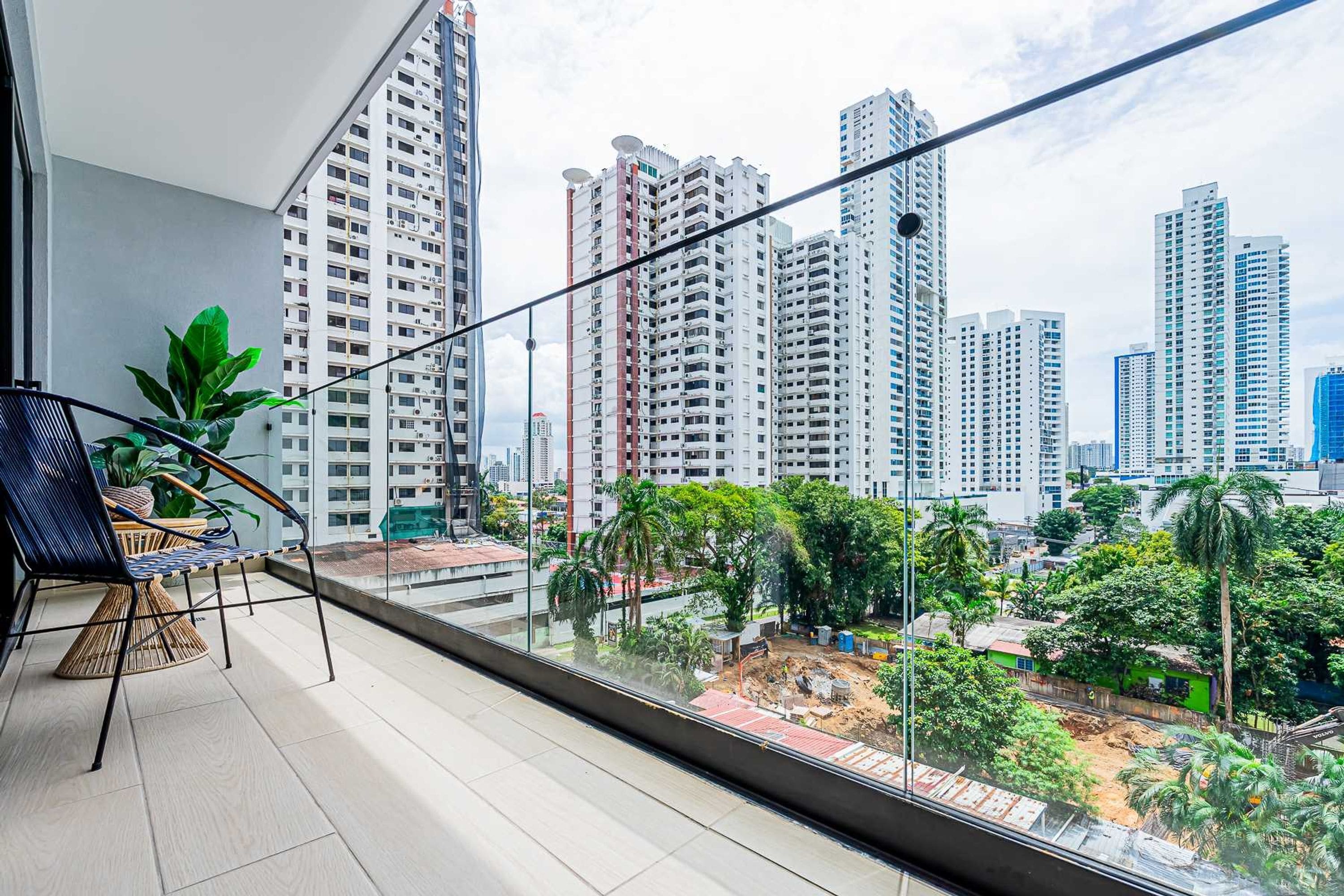 A balcony with a view of high-rise buildings and greenery.