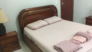 A neatly made bed with a wooden headboard, a bedside table with a lamp, and a small drawer unit. - Botanical Garden House, Tororó Waterfall (Brasília)