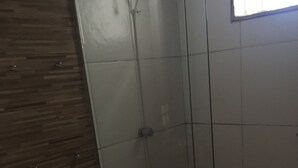 A bathroom with a toilet, a glass shower enclosure, and a wooden wall. - Botanical Garden House, Tororó Waterfall (Brasília)