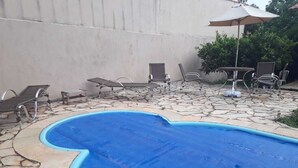 A swimming pool with lounge chairs and a table with an umbrella. - Botanical Garden House, Tororó Waterfall (Brasília)