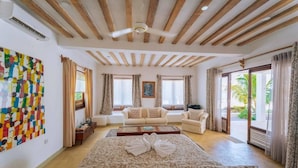 Ein geräumiges Zimmer mit einem großen Bett, zwei Sofas, einem Couchtisch und einem Deckenventilator.