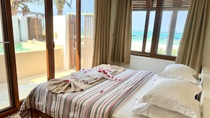 Ein Hotelzimmer mit Bett, Blick auf den Strand und einer Schiebetür.