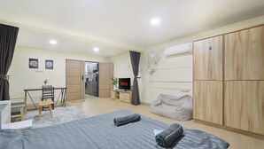Quarto moderno com cama, escrivaninha, televisão e guarda-roupa.