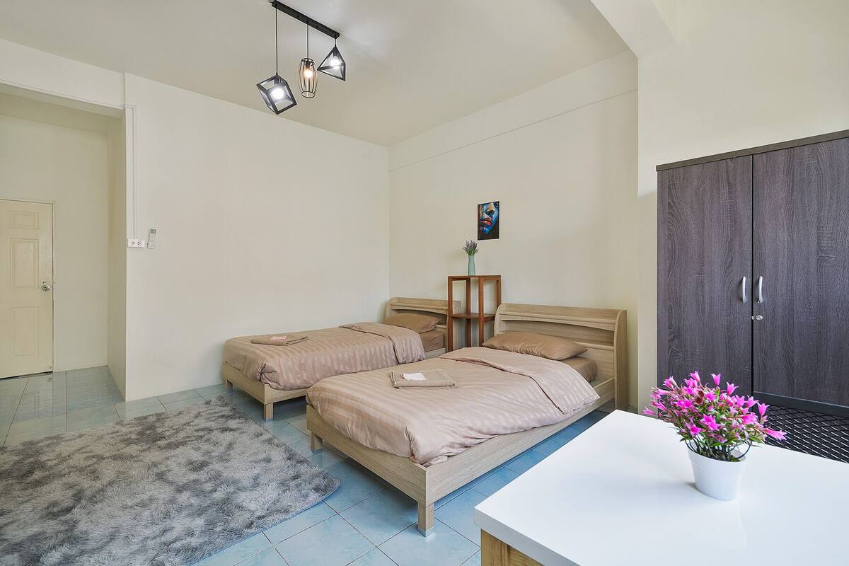 Een slaapkamer met twee bedden, een bureau, een kledingkast en een plafondlamp.