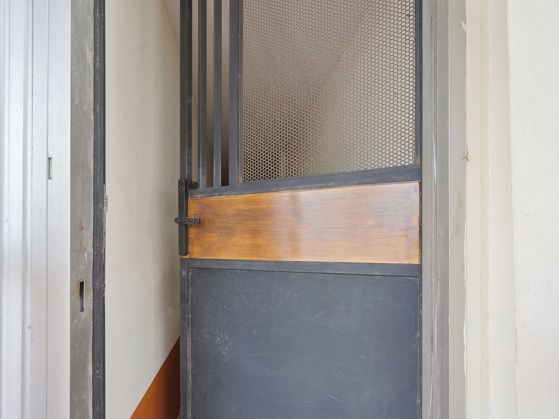 A door with a metal frame, a wooden panel, and a mesh screen.