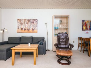 Un salon comprenant un canapé, une table en bois, un fauteuil en cuir et une vitrine avec des étagères.