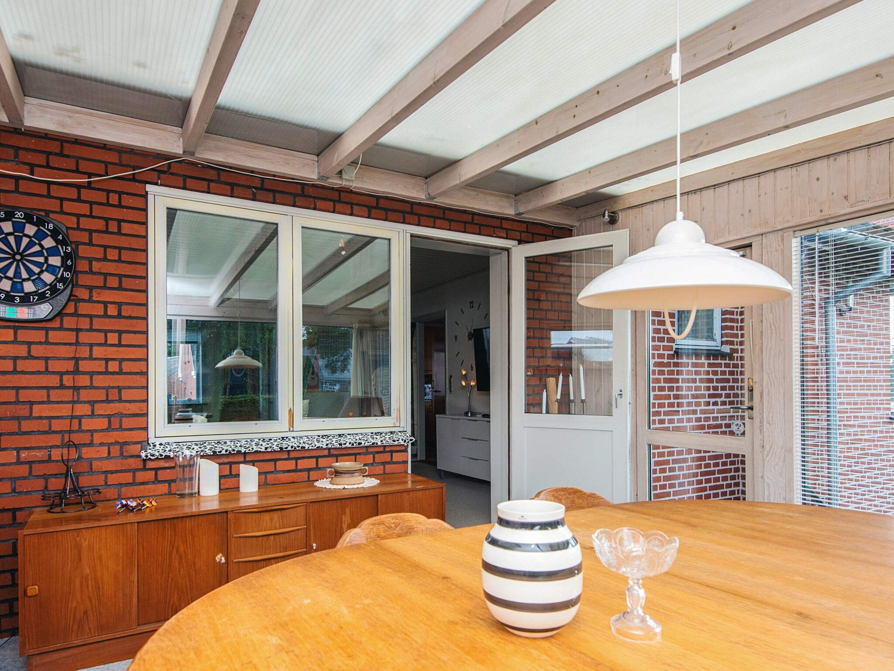 A dining area with a wooden table, a vase, and a lamp.