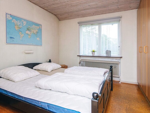 A bedroom with two beds, a world map, a window with a view, and a radiator.