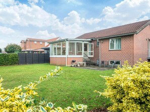 A residential house with a brick exterior, a conservatory, a lawn, and a garden with yellow foliage. - 6 Person Holiday Home in Ansager (Ansager)