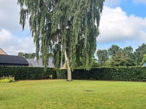 A tree-lined yard with a well-maintained lawn and a hedge. - 6 Person Holiday Home in Ansager (Ansager)