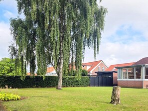 A residential area with a large tree, a well-maintained lawn, and a brick house with a glass conservatory. - 6 Person Holiday Home in Ansager (Ansager)