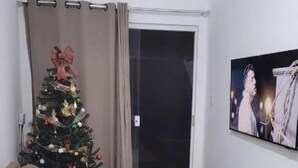 Een woonkamer met een bruine bank, een kerstboom en een schilderij aan de muur.