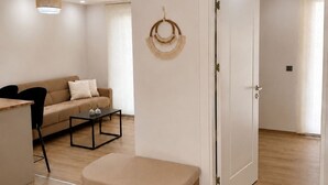 Ein modernes Wohnzimmer mit Sofa, Couchtisch, Pouf und einer Wanddekoration.