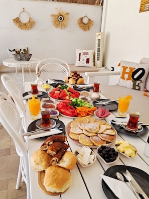 Una mesa de desayuno con una variedad de alimentos, como panqueques, pan y frutas frescas.