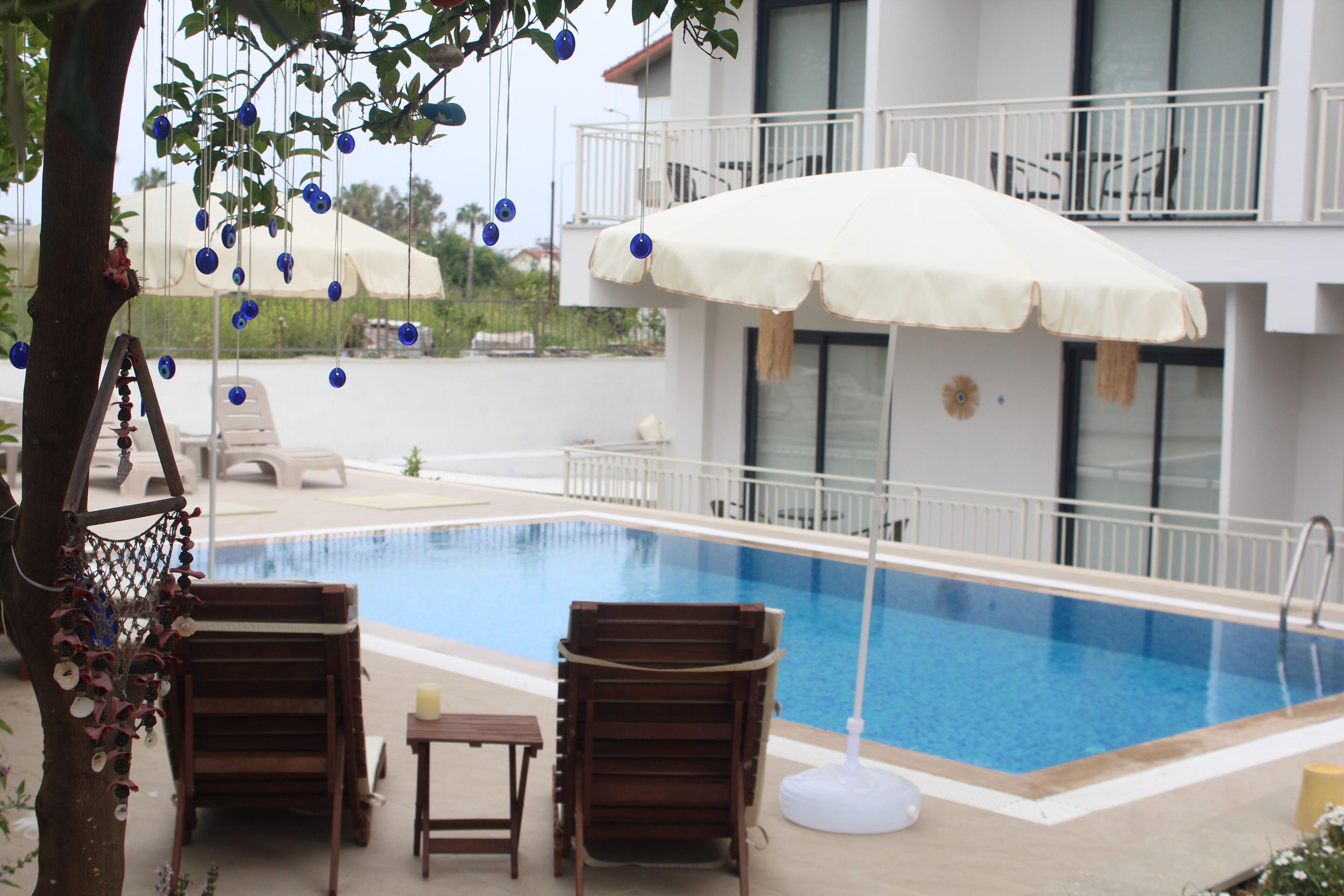 Ein Swimmingpool mit Liegestühlen und einem Tisch, umgeben von einem Gebäude mit Balkonen.