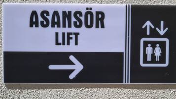A directional sign with "ASANSÖR LIFT" and an arrow pointing right, indicating the location of a lift.