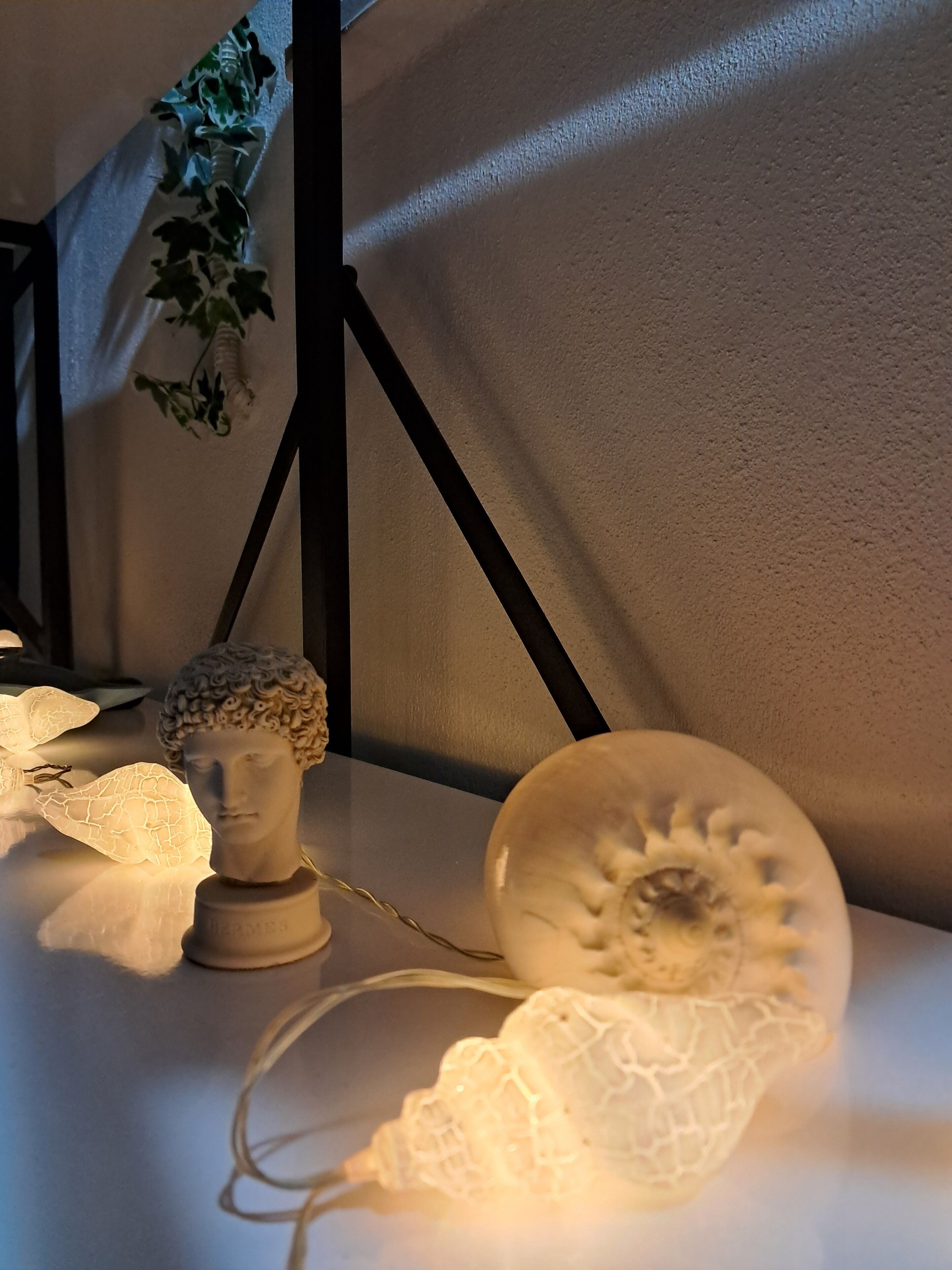 Una stanza con parete decorata, una piccola scultura a busto e oggetti in vetro ornamentali.