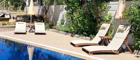 A swimming pool with lounge chairs and umbrellas.
