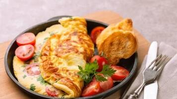 A breakfast plate with an omelette, tomatoes, parsley, and a piece of toast.