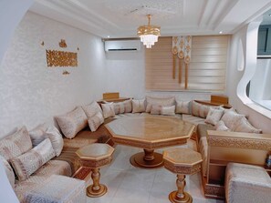 Ein luxuriöses Wohnzimmer mit einem großen, achteckigen Couchtisch, passenden Hocker und einer Deckenleuchte.