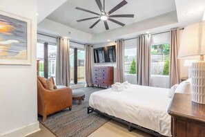 A modern hotel room with a large bed, a sofa, a TV, and a view of the outdoors. - Riverside Bungalow - Private Pool in East Nash (Nashville)