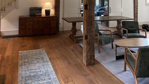 A spacious living area with a wooden ceiling, a dining table, and a sofa. - Copper Kettle Farm - newly renovated farmhouse with spectacular views (Sheffield)