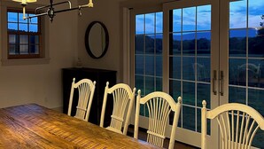 A dining area with a wooden table, white chairs, and a chandelier. - Copper Kettle Farm - newly renovated farmhouse with spectacular views (Sheffield)