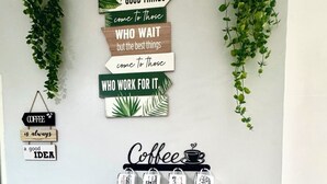 A kitchen counter with a coffee maker, a coffee mug rack, and decorative signs. - Gorgeous Modern Condo in Bacolod City (Bacolod)