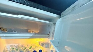 An open refrigerator with shelves containing bottled water and a clear plastic container. - Gorgeous Modern Condo in Bacolod City (Bacolod)