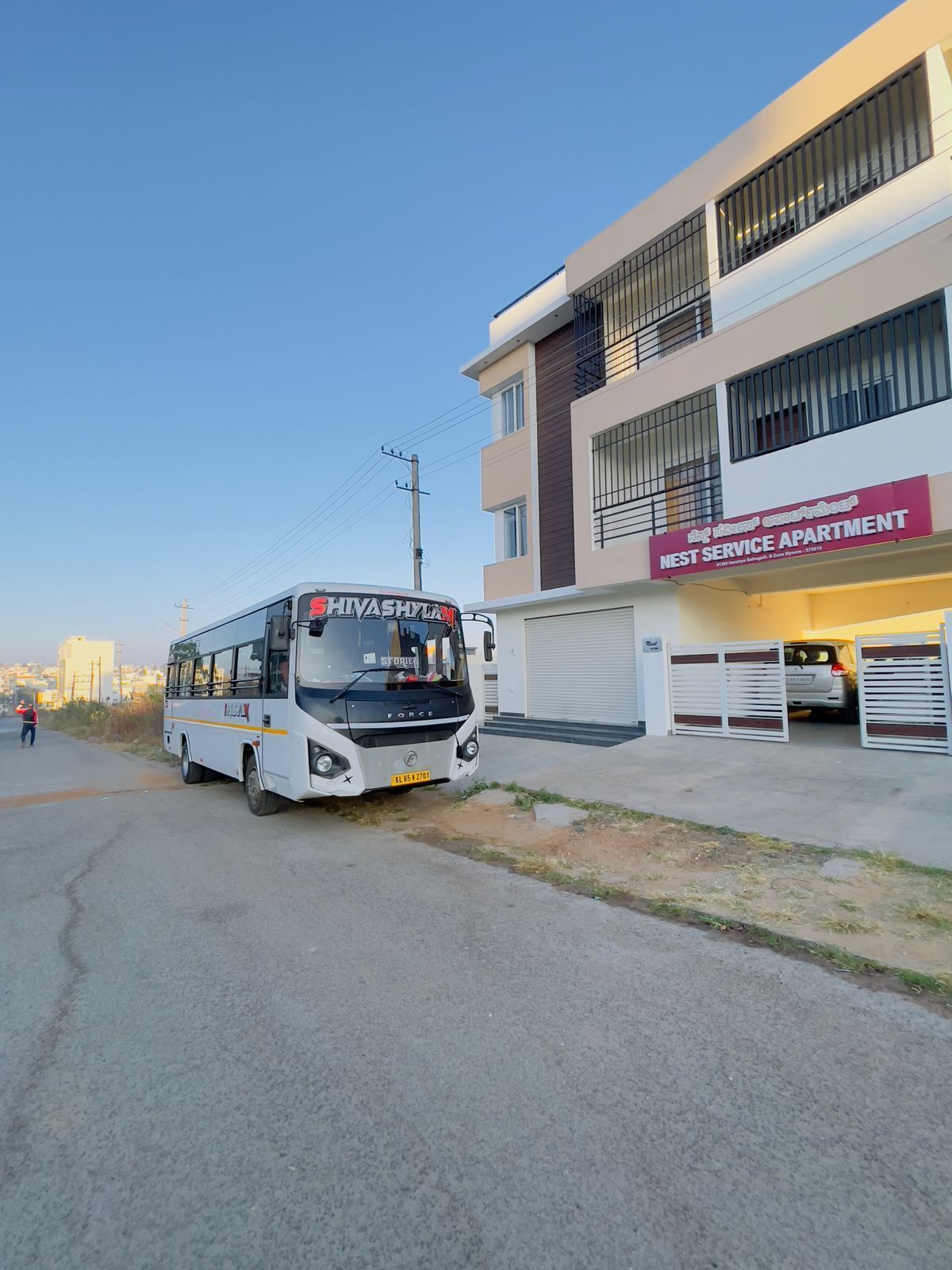 A bus parked in front of a building with a sign that reads "West Service Apartment".