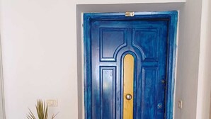 A blue door with a yellow panel, a potted plant, and a tiled floor. - Apartment in Hammamet nord sea and mountain view (Nabeul‎)
