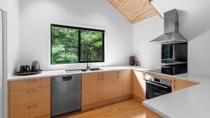 Cocina moderna con lavavajillas, horno y un amplio ventanal con vistas a la vegetación.
