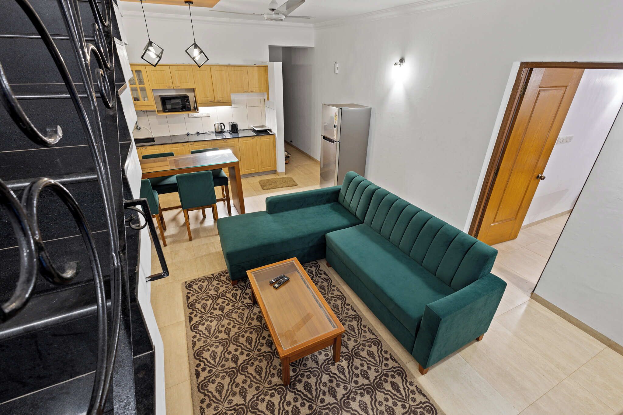 A modern living room with a green sofa, a wooden coffee table, and a patterned rug.