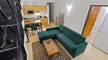 A modern living room with a green sofa, a wooden coffee table, and a patterned rug.