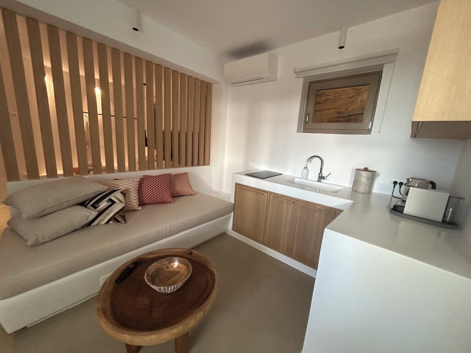 A compact kitchen with a built-in sink, a wooden cabinet, and a small wooden table with a bowl.