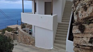 A modern house with a stone exterior, a wooden staircase, and a view of the sea. - ANDELIAS SIGNATURE SUITES  (Folegandros)