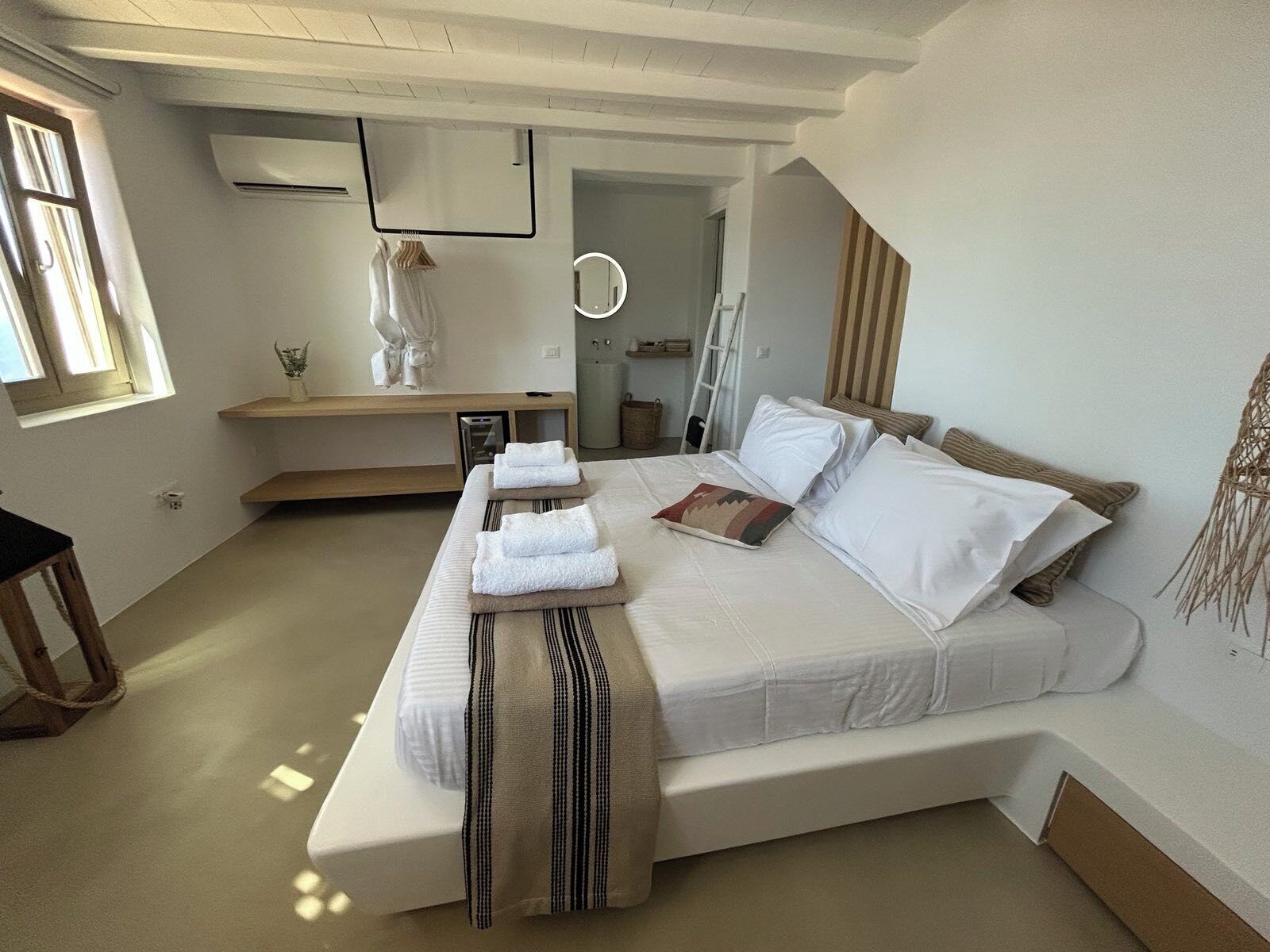 A modern bedroom with a large bed, bedside tables, a vanity, and a mirror.