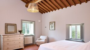A bedroom with a bed, a dresser, a chair, and two windows.