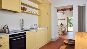 A kitchen with yellow cabinets, a stove, and a sink. There is a dining area with a table and chairs visible through an open doorway.