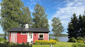 A red cabin with a black roof, surrounded by greenery and a lake. - Swedish house directly on the lake with motorboat & own boat ramp (Storfors)