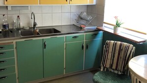 A kitchen with green cabinets, a sink, and a window with a plaid curtain. - Swedish house directly on the lake with motorboat & own boat ramp (Storfors)