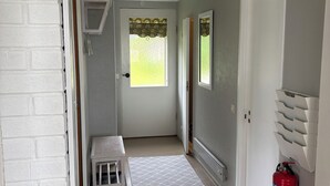 A hallway with a white door, a fire extinguisher mounted on the wall, a small bench, and a patterned rug. - Swedish house directly on the lake with motorboat & own boat ramp (Storfors)
